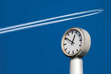 Time and Speed: Clock and Airplane in the blue Sky
