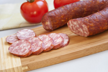 Smoked sausage on a cutting board and fresh tomatoes