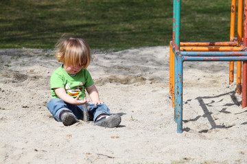Fototapeta na wymiar Kleiner Jugen spielt alleine im Sand