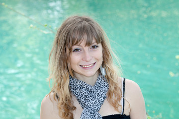 young blond girl smiling in front of a lake