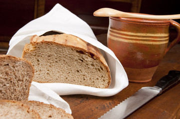fresh bread with cup of milk and wooden spoons
