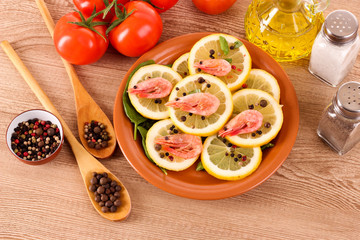 Shrimp on lemons with tomato, peppers and oil on wooden table