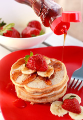 Syrup pouring on top of pancakes.