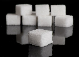 Lump sugar (sugar cubes) on black reflective background