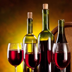 Still life with wine bottles, glasses and oak barrels.