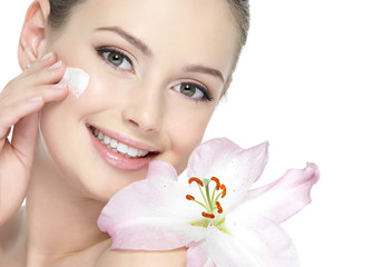 Happy smiling girl with lily applying cream