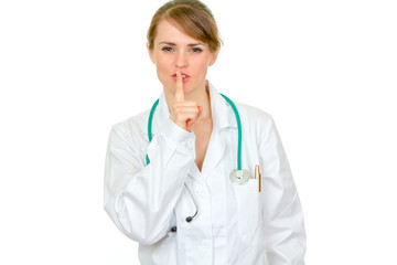 Authoritative doctor woman with finger at mouth. Shh gesture.