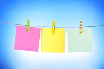 Blank paper sheets on a clothes line on a blue background