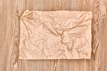 Brown crumpled paper on wooden texture