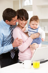 Parents With Baby Working From Home Using Laptop