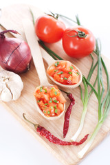 Salsa in two spoons on a wooden board and ingredients