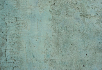 worn blue mint green wall with some damage and cracks