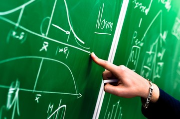 Hand of a student pointing at green chalk board