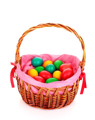 Wicker basket with Easter eggs isolated on white