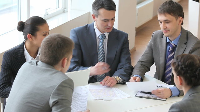 High angle view of professional business team working together, analyzing documents, exchanging ideas, then looking at camera. Great for office life and corporate content