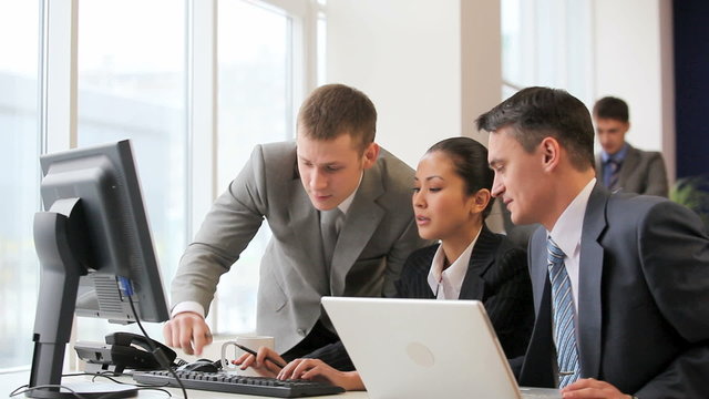 Businesspeople looking at monitor of computer and talking