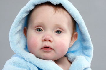 Adorable baby boy in a blue bathrobe