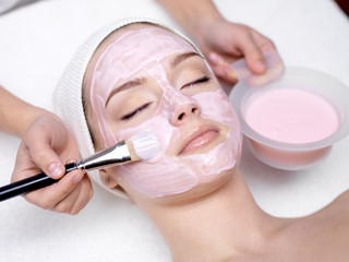 Girl receiving cosmetic pink facial mask - obrazy, fototapety, plakaty