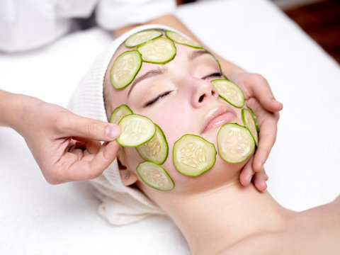 Woman receiving facial mask of cucumber