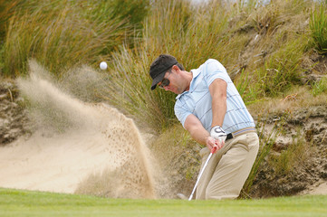 Golfer plays green side bunker shot