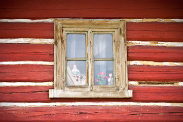 Obraz na płótnie Canvas Old wooden window in the wall of cottage with few dolls inside