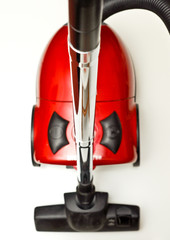 Fototapeta premium The red vacuum cleaner with a black hose on a white background.