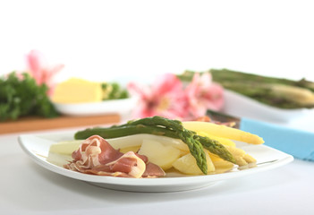 Green and white asparagus on potatoes with ham