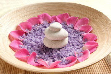 Fototapeta na wymiar A spa composition of petals, purple salt and white stones