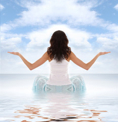 Fototapeta na wymiar A young and fit Caucasian woman is meditatin on the water