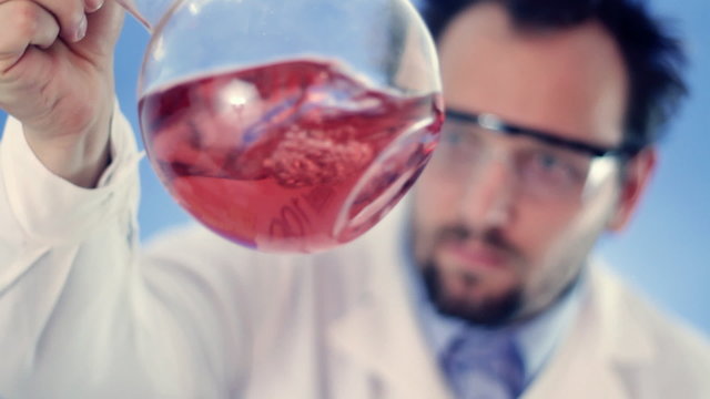 Male scientist mixing Volumetric flask with red liquid