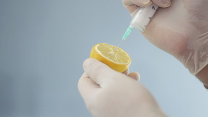 Male scientist hands with syringe injecting lemon - Powered by Adobe