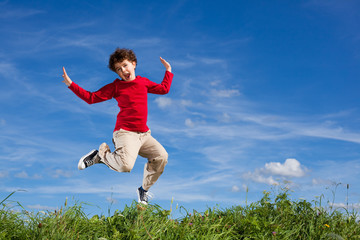 Boy jumping, running against blue sky