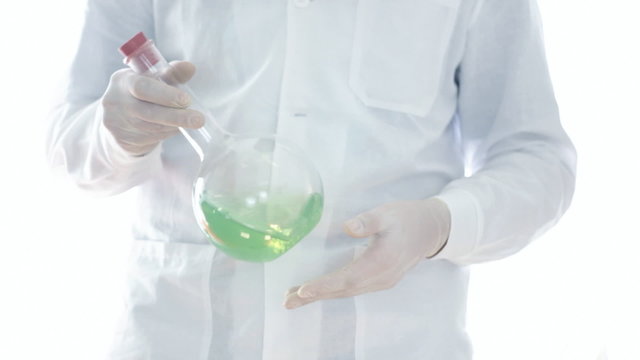 Male scientist examining volumetric flask with green liquid