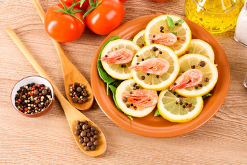 Shrimp on lemons with tomato, peppers and oil on wooden table