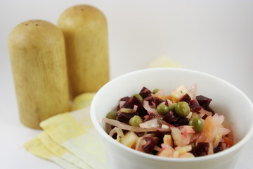 Russian vinaigrette salad in a white plate with salt and pepper