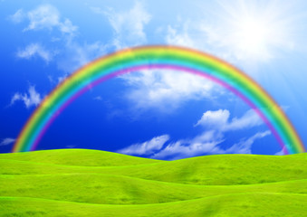 Rainbow in the blue sky over a glade