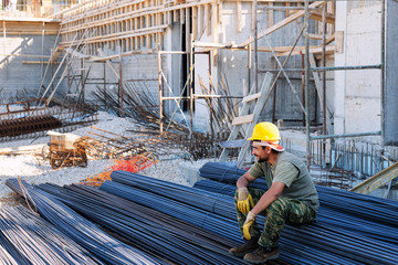 Construction worker resting on steel bars