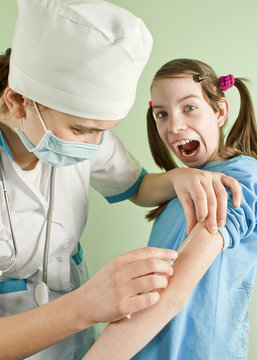 Lady doctor making an injection to scared teen girl