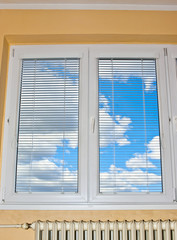 Blue sky with thick white clouds behind closed window.