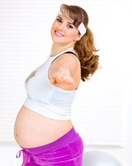 Smiling beautiful pregnant woman doing exercise at living room.