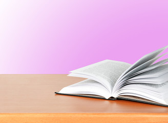 Open book on desk  on pink background