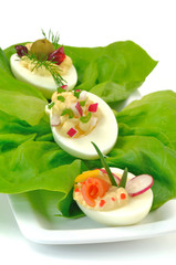 połówki jajek z kolorowym farszem na liściach sałaty