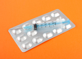 Syringes and tablets on orange