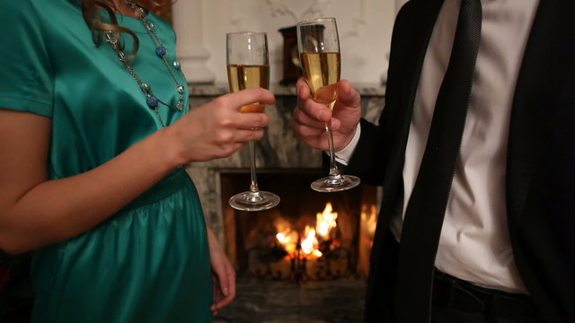 Smart couple clinking flutes with champagne at party