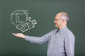 lehrer mit computer an der tafel