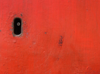 old key-hole embedded in worn red metal surface © johnjohnson