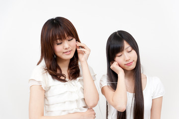 two beautiful asian women listening to music