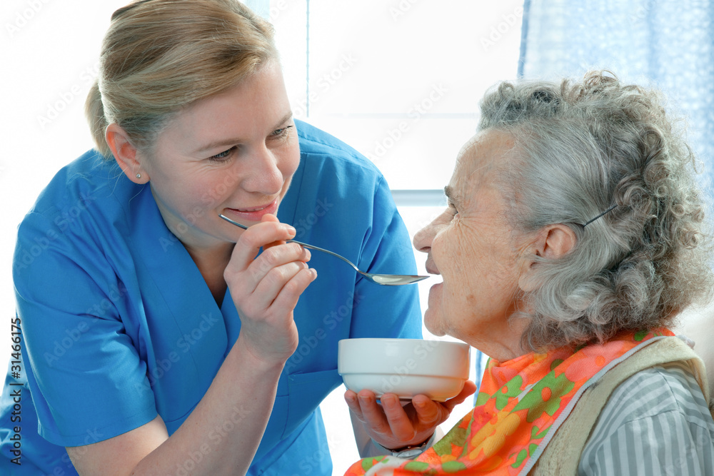 Wall mural senior woman 90 years old being fed by a nurse