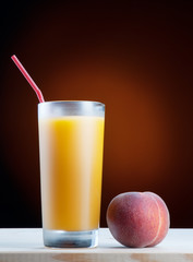 Fresh peach juce in glass on dark background