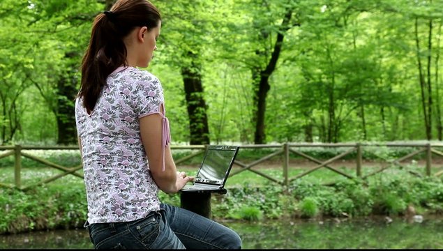 Ragazza che lavora al pc in riva a un lago